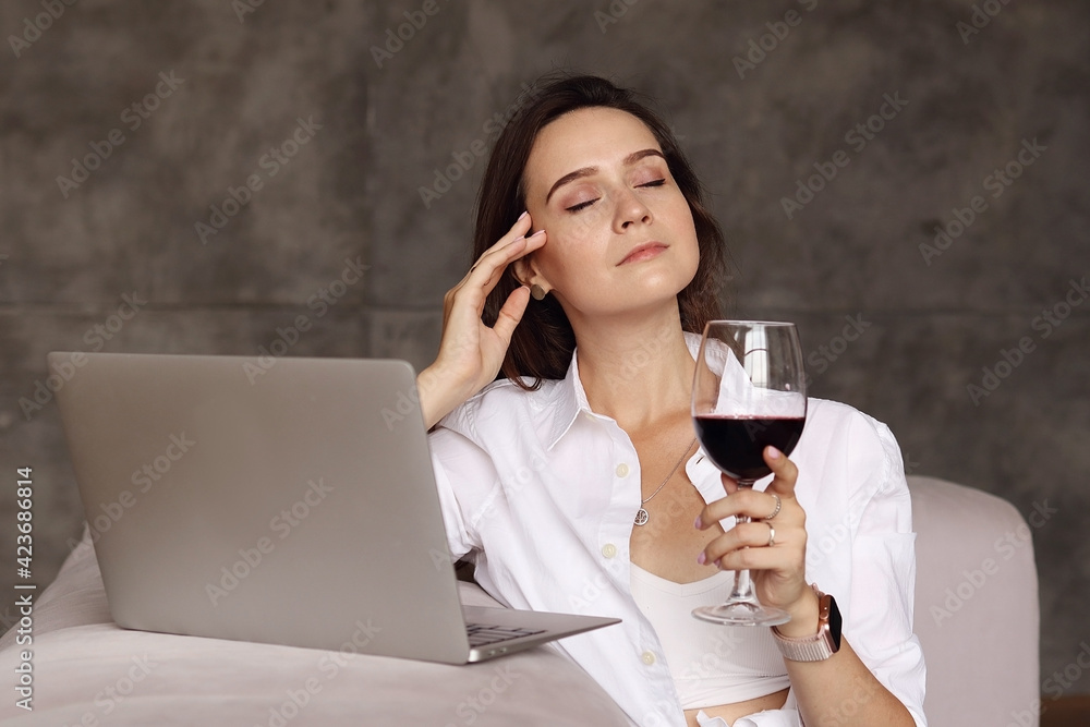 Tired woman after work drinks a glass of red wine Tired woman after work drinks a glass of red wine