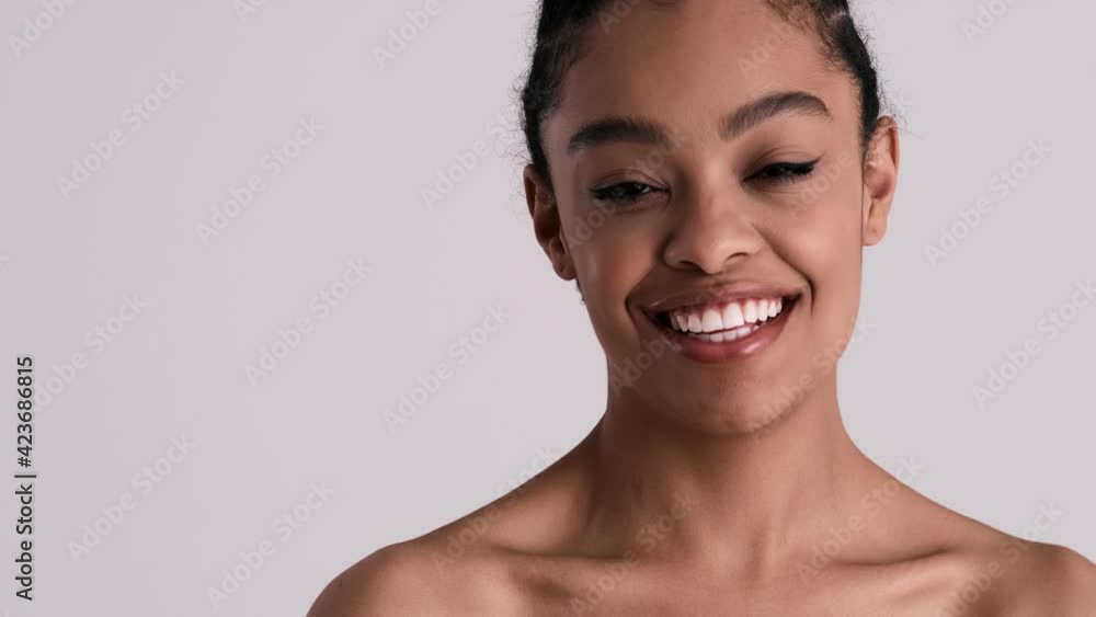A happy young half-naked woman is looking to the camera standing isolated over gray background in studio A happy young half-naked woman is looking to the camera standing isolated over gray background in studio