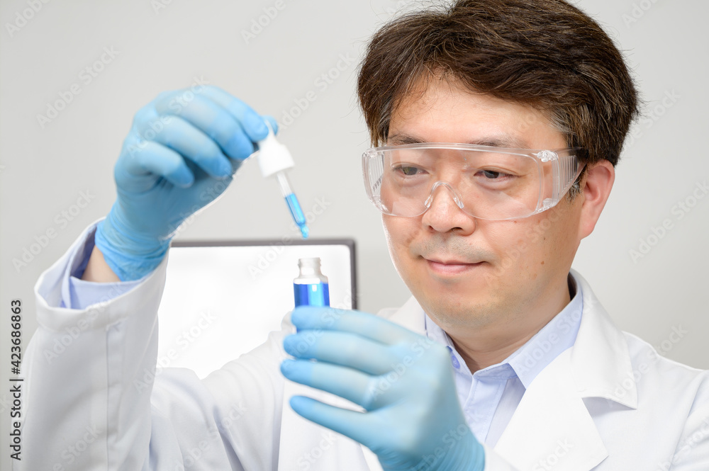 Portrait of a middle-year Asian male scientist wearing a white lab gown and gloves and holding an experimental container in his hand. Portrait of a middle-year Asian male scientist wearing a white lab gown and gloves and holding an experimental container in his hand.