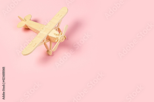 wooden model of a passenger plane with on a pink background. tourism and travel concept.
