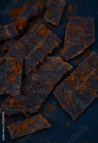 Beef jerky with hot pepper on black stone surface. Dried meat.