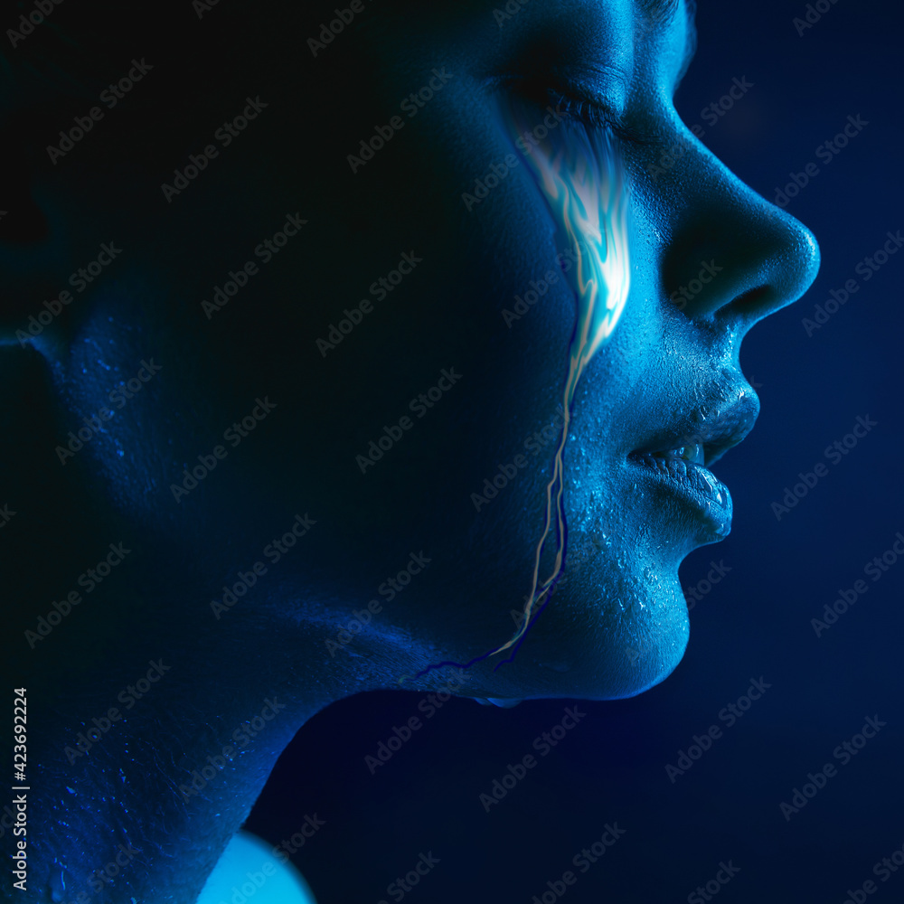 Portrait of young beautiful woman with neon, fluid tears from eyes. Concept of fashion and beauty, emotions and feelings, modern design
