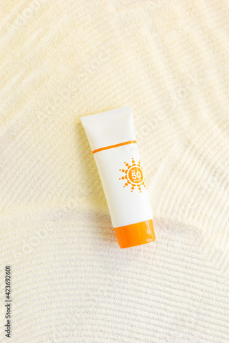 white cosmetic tube  with sun protection cream spray on sand textured background . Cosmetic products  with spf. UV protection concept. Copy space
