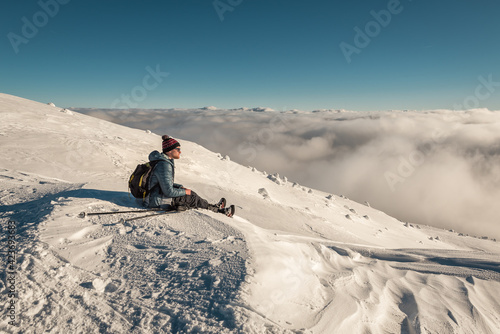 hiker sitting on the snow in winter mountains