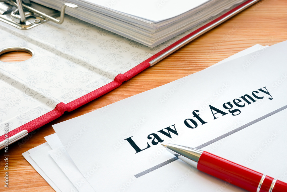 Law of agency papers near folder with contract. Law of agency papers near folder with contract.