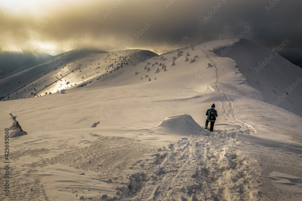 hiker with a backpack walks on a snowy mountain range