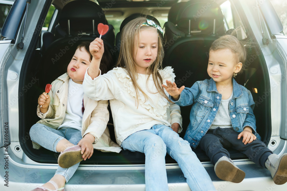 Little kids sitting in a car's trunk before a road trip