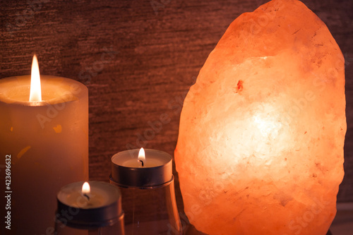 Himalayan salt lamp with, candles in dark room. Spa, relax concept.