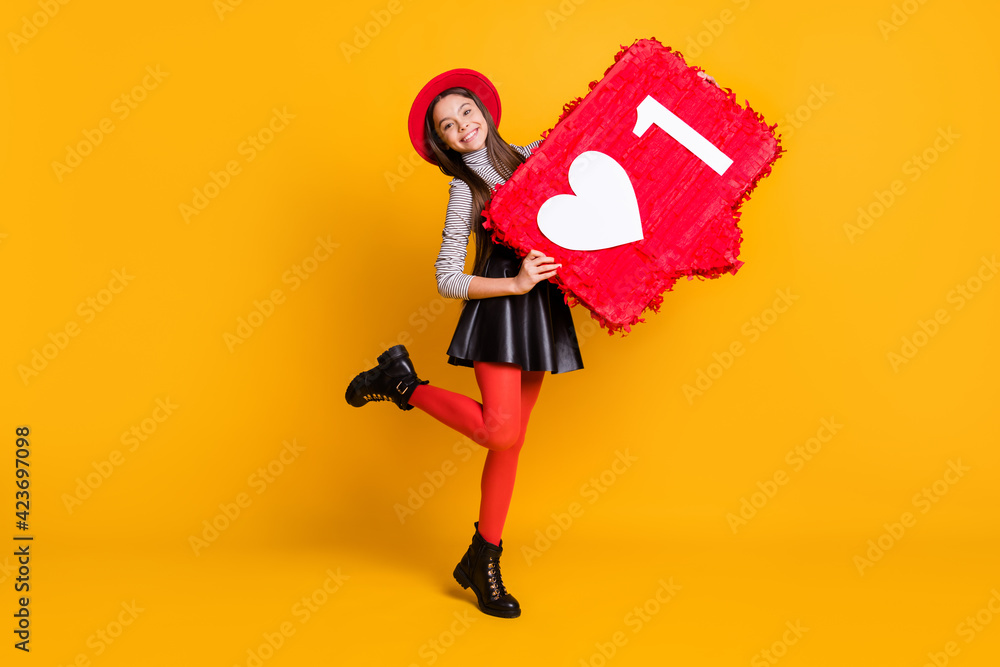 Full length body size view of pretty trendy cheerful girl holding in hands big like board having fun isolated over bright yellow color background Full length body size view of pretty trendy cheerful girl holding in hands big like board having fun isolated over bright yellow color background