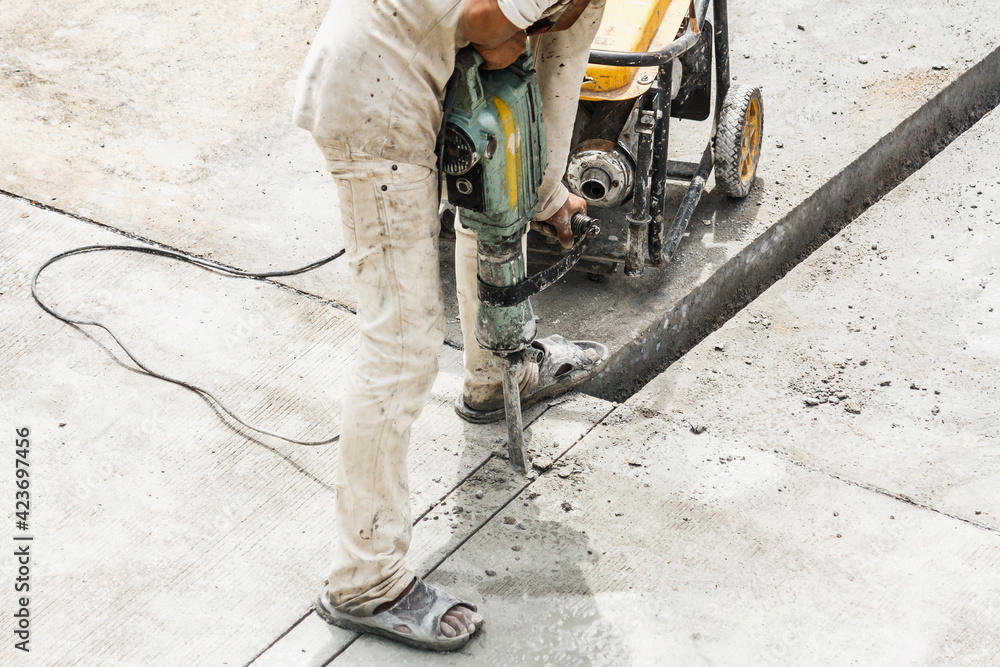 Construction worker using jackhammer drilling concrete surface Construction worker using jackhammer drilling concrete surface