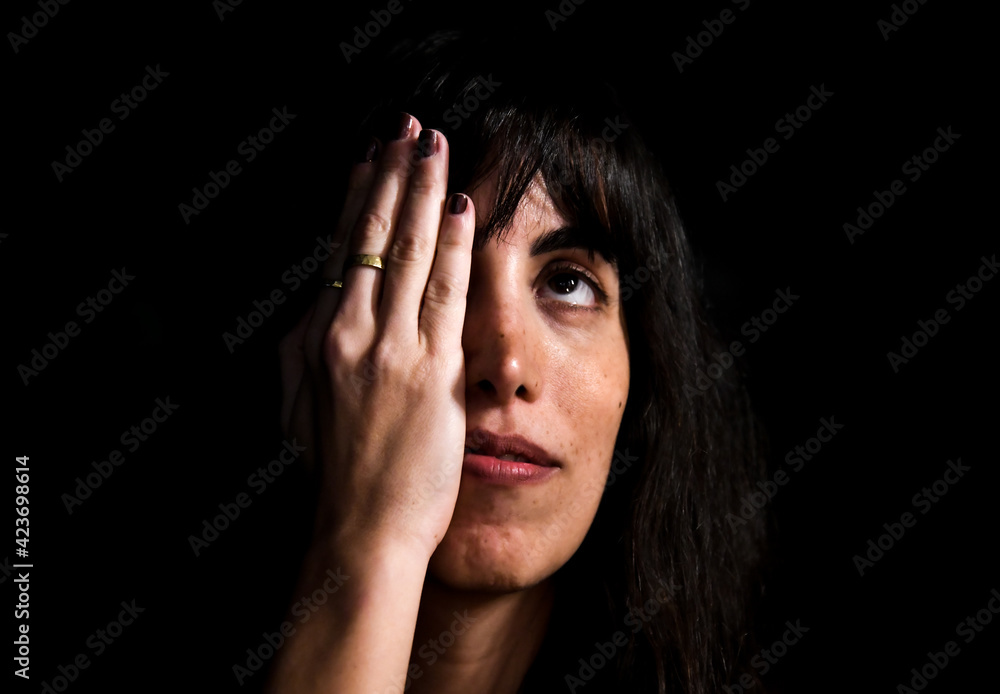 portrait of an attractive woman covering half of her face with her hand and looking upclosed eye portrait of an attractive woman covering half of her face with her hand and looking upclosed eye