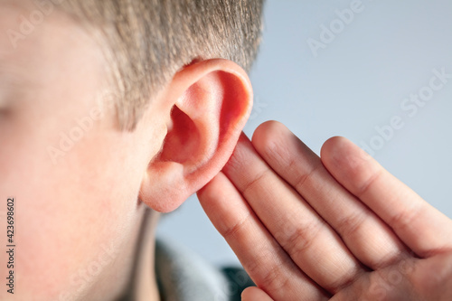 Quadro su tela Boy with hand on ear listening for quiet sound or paying attention