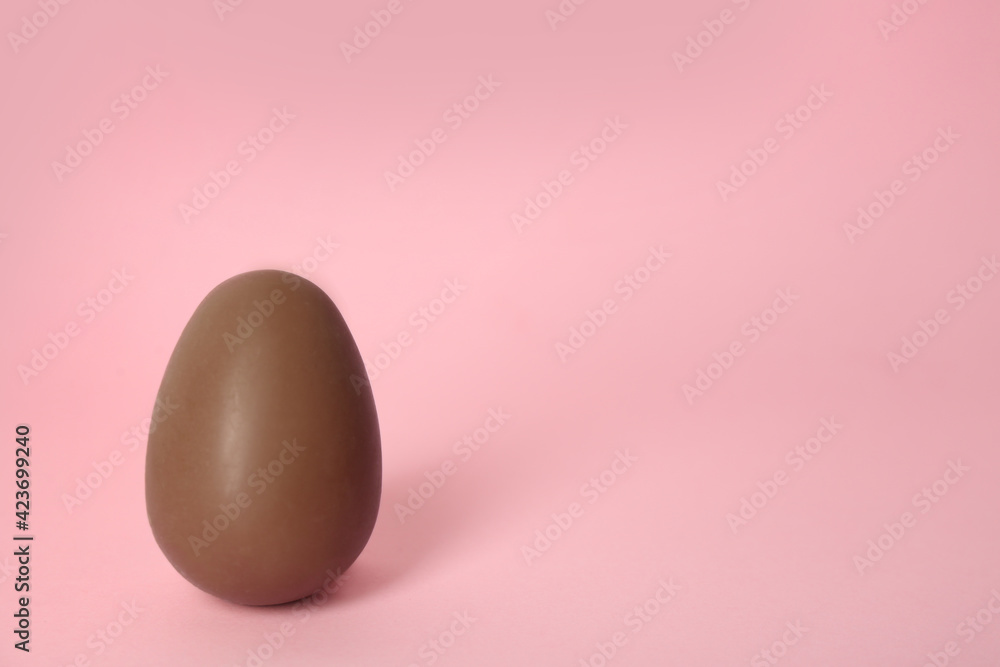Sweet chocolate egg on pink background. Space for text Sweet chocolate egg on pink background. Space for text