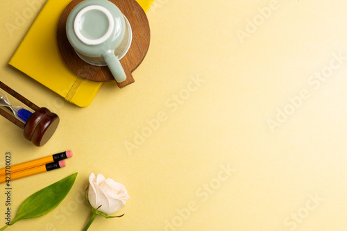 Notebook, sandglass, pencil, mug cup, rose on yellow gold background. Work and study place. flat lay, top view, copy space