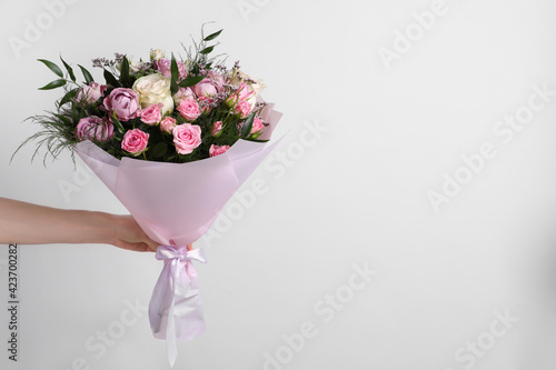 Leinwand Poster Woman with bouquet of beautiful roses on light background, closeup