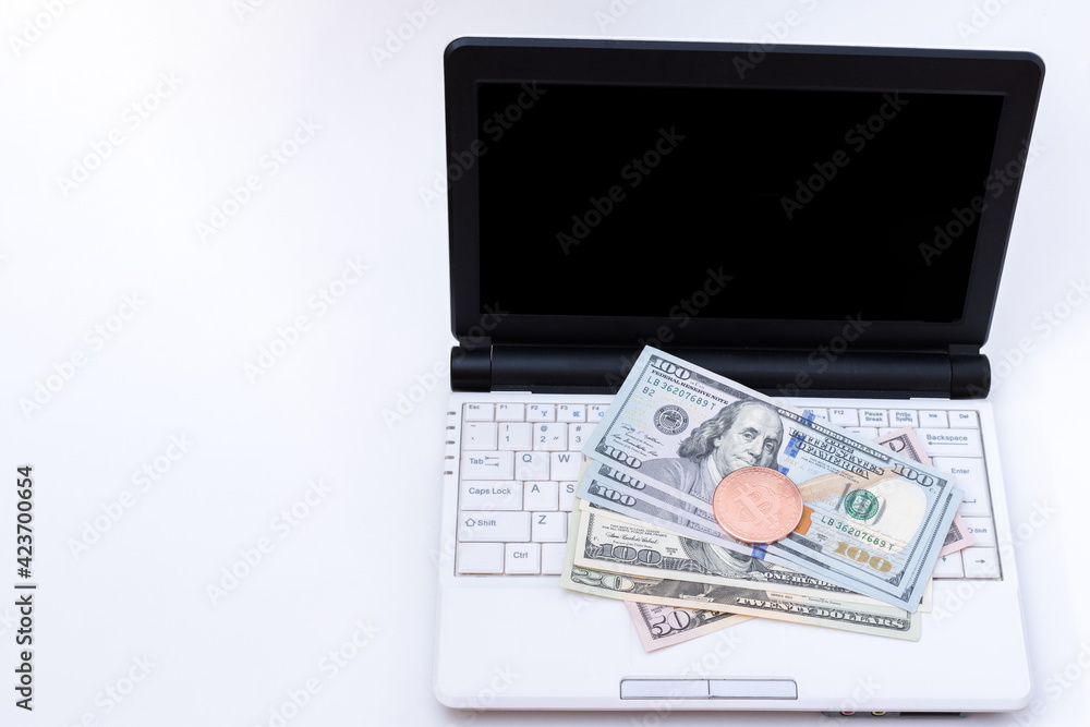 Bitcoin BTC virtual money on one hundred dollar paper bills on laptop keyboard with black screen on white background, copy space. Bitcoin cryptocurrency concept. USD to BTC. Blockchain technology Bitcoin BTC virtual money on one hundred dollar paper bills on laptop keyboard with black screen on white background, copy space. Bitcoin cryptocurrency concept. USD to BTC. Blockchain technology