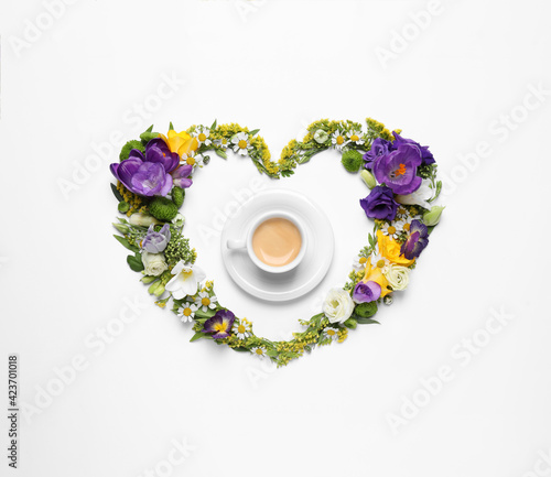 Beautiful heart made of different flowers and coffee on white background, top view
