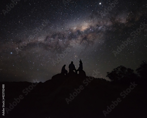 Silhouette of a group of person Sitting on a Rock Watching the Milkyway © nicolas