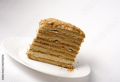 A piece of homemade honey cake with many layers on a white plate
