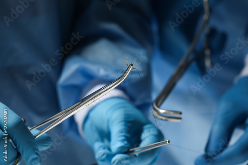 Φωτογραφία Professional surgeons with forceps and suture thread, closeup