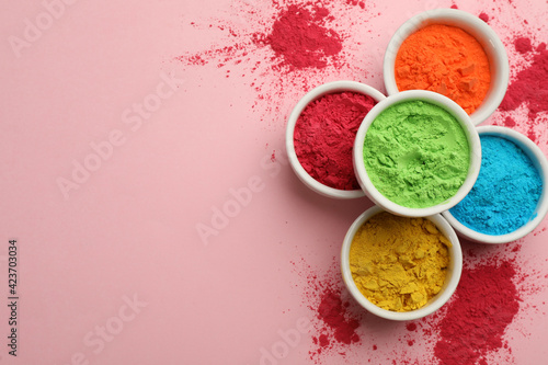 Colorful powders in bowls on pink background, flat lay with space for text. Holi festival celebration photo