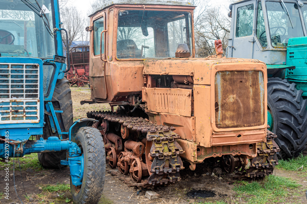 Abandoned farm equipment. Old tractors are rusty and broken.