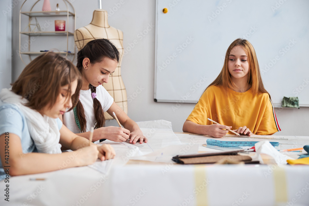 Three adorable girls working in sewing workshop Three adorable girls working in sewing workshop