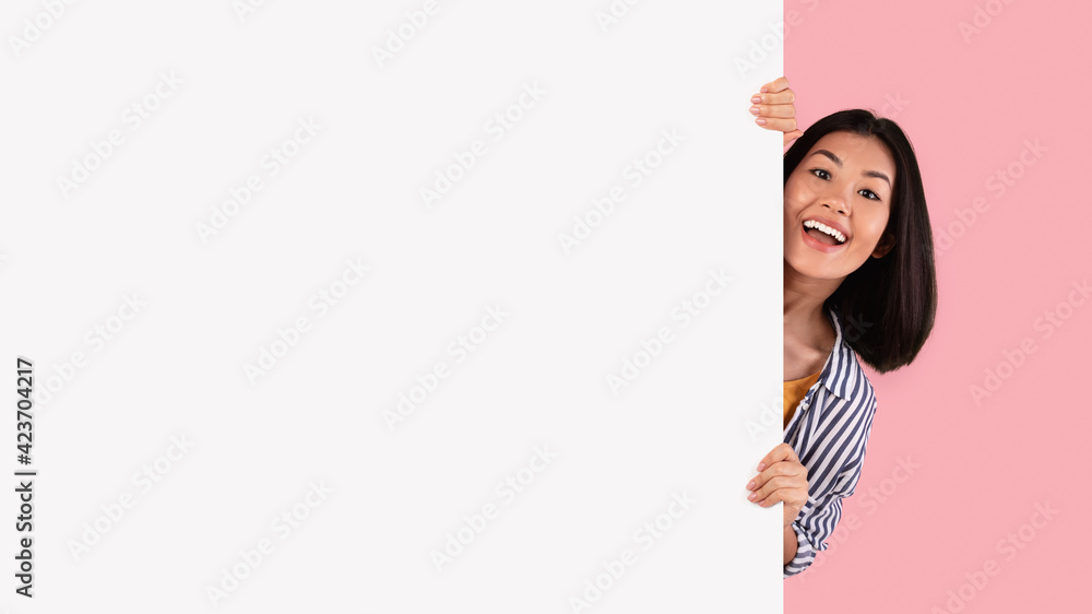 Asian woman hiding behind blank white advertising billboard Asian woman hiding behind blank white advertising billboard