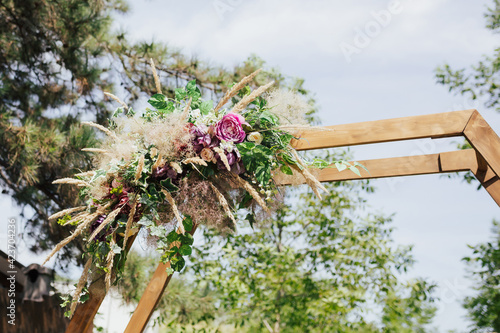 Obraz na płótnie Close-up of flowers and greenery on a beautiful wooden wedding arch. Preparing for the wedding event in the forest. w salonie