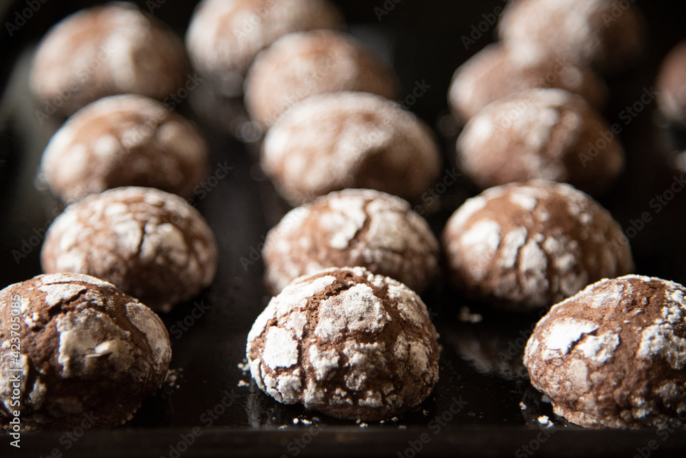 Cracked chocolate cookies with icing sugar on a pan Cracked chocolate cookies with icing sugar on a pan
