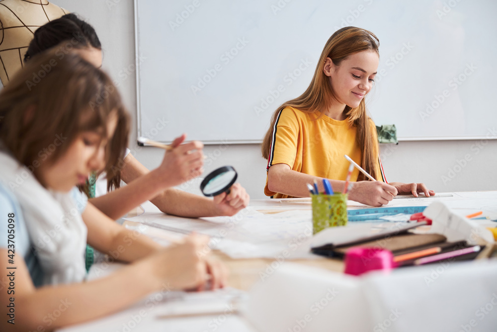 Cute children drawing clothes patterns in sewing workshop Cute children drawing clothes patterns in sewing workshop