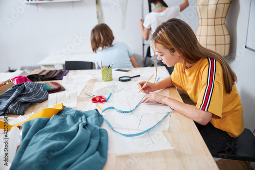 Canvastavla Cute girl drawing clothes patterns in sewing workshop