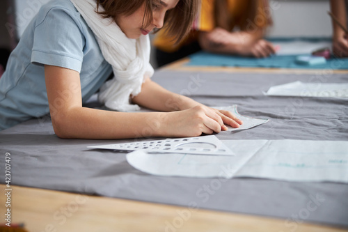 Adorable girl preparing fabric in sewing workshop