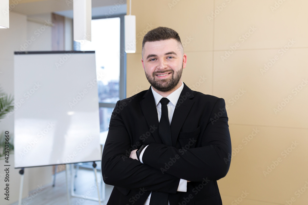 Portrait young bearded man in a formal black business suit with glasses and tie looking at camera. Confident Male a modern office a whiteboard. Manager ceo meeting or conference person, businessman Portrait young bearded man in a formal black business suit with glasses and tie looking at camera. Confident Male a modern office a whiteboard. Manager ceo meeting or conference person, businessman