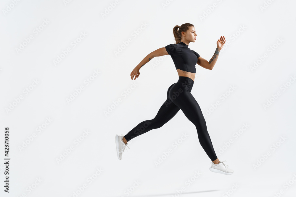 Woman runner in silhouette on white background. Dynamic movement. Side view of female jogger, sportswoman in sport clothing in air, jumping or running on white studio copy space