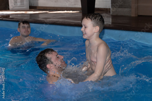 A Dad with happy baby swims in the pool