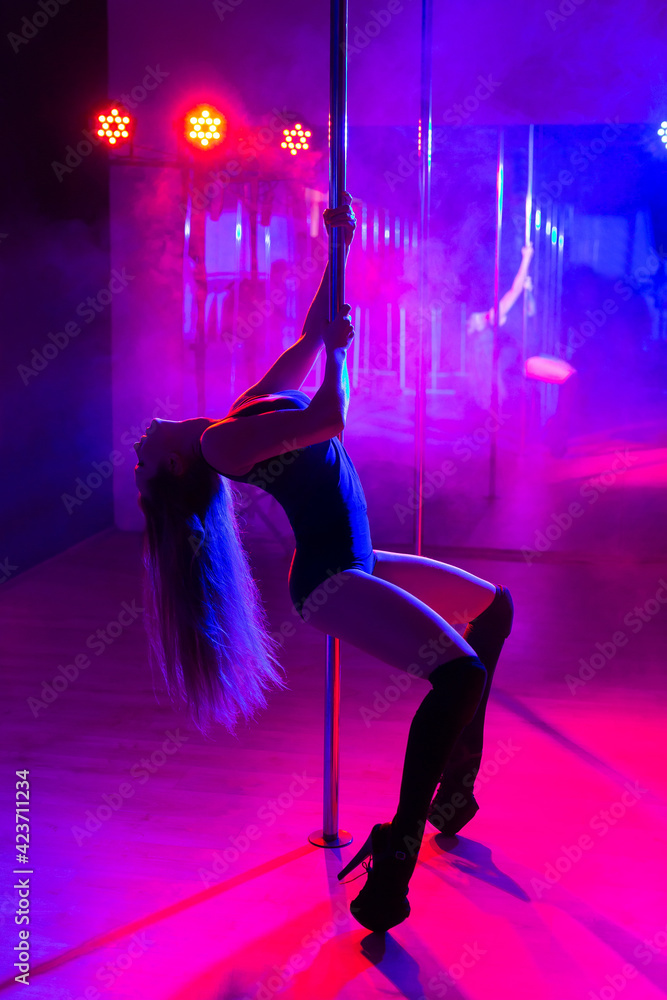 Pole dance. Slender sexy woman dancing in the interior of a nightclub with  a colored background and smoke. Stock Photo | Adobe Stock