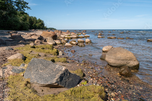 Coastline of the Baltic Sea full of big and small rocks during sunny summer day