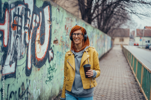 Woman listening music on a headphones and drinking coffee