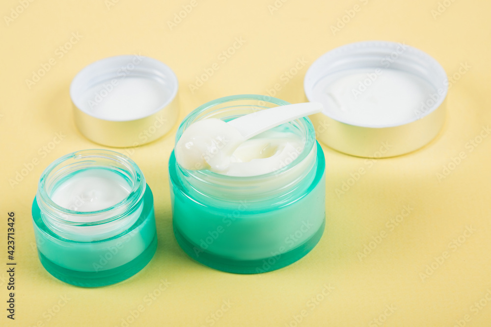 White cream in a blue jar on a yellow background. White cream in a blue jar on a yellow background.