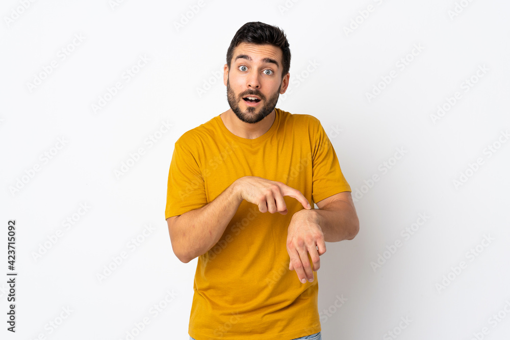 Young handsome man with beard isolated on white background making the gesture of being late Young handsome man with beard isolated on white background making the gesture of being late