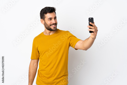 Young handsome man with beard isolated on white background making a selfie