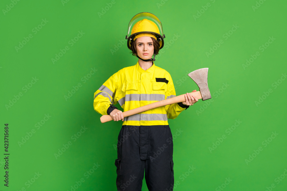 Photo of cute confident young fire lady workwear yellow helmet holding ax isolated green color background Photo of cute confident young fire lady workwear yellow helmet holding ax isolated green color background