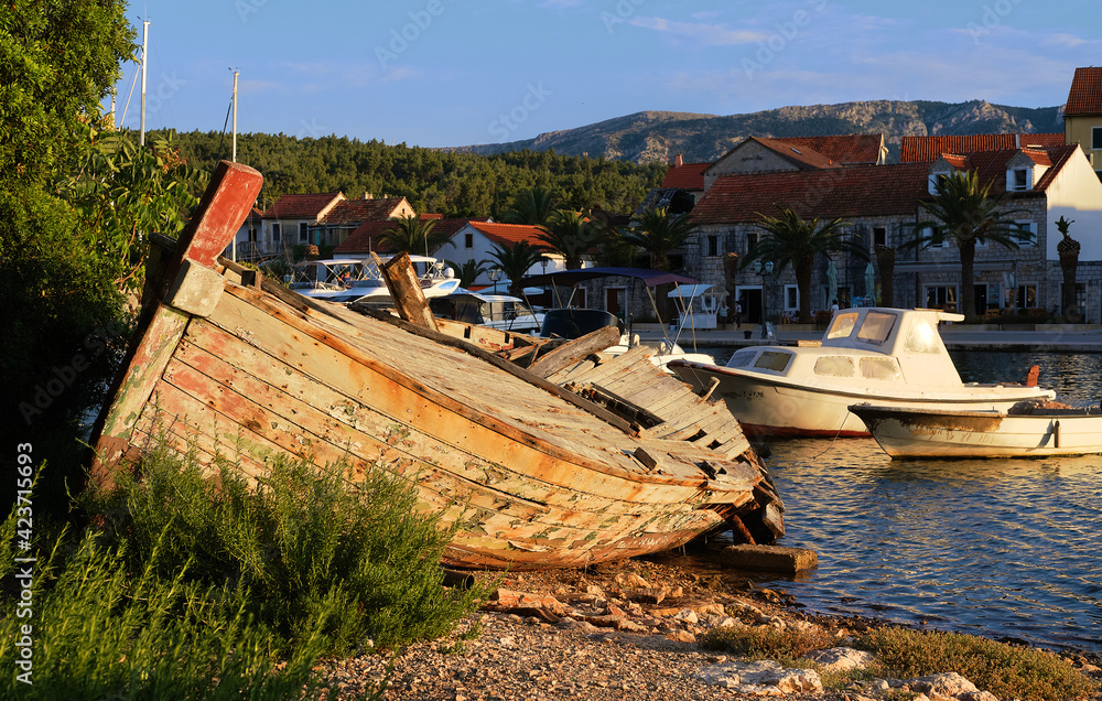 Abandoned fisherman boat on the coastline of inland sea channel in Vrboska villag, Hvar island, Dalmatia, Croatia.