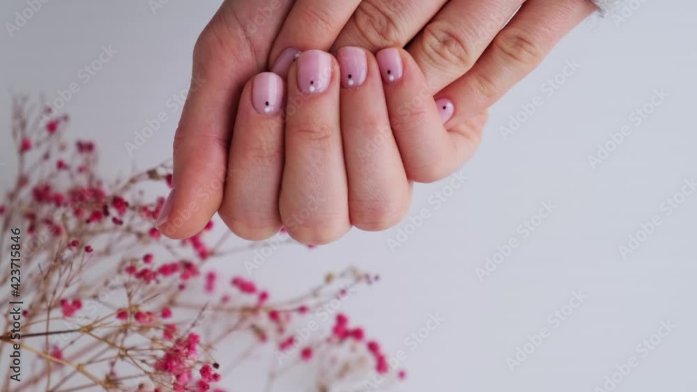 Woman showing hands with beautiful nude manicure holding delicate pink
