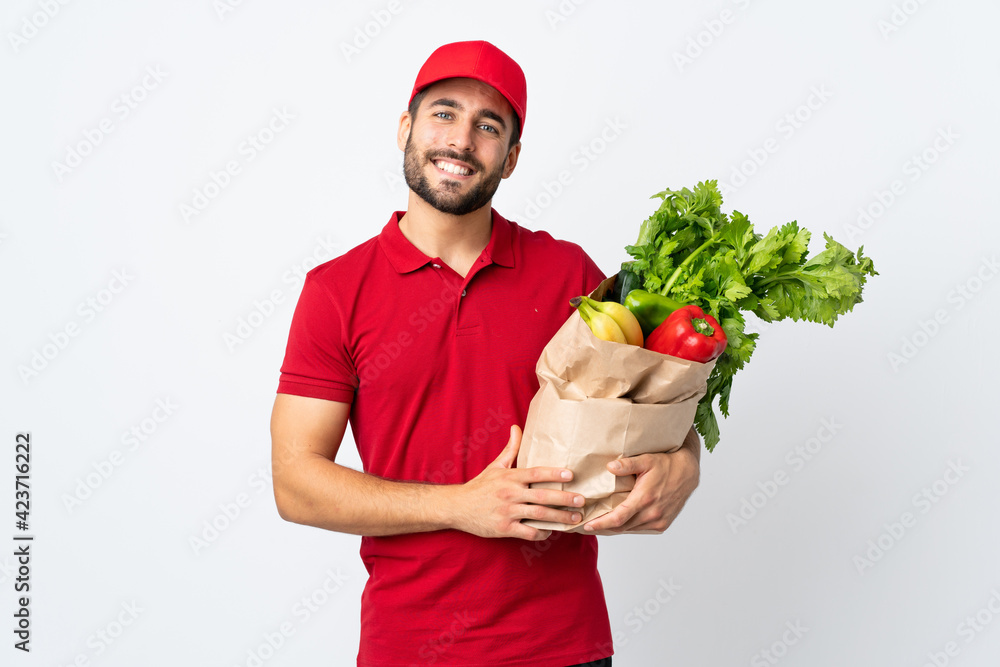 Young man with beard holding a bag full of vegetables isolated on white background applauding Young man with beard holding a bag full of vegetables isolated on white background applauding