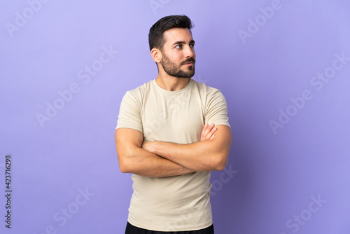 Young handsome man with beard over isolated background looking to the side
