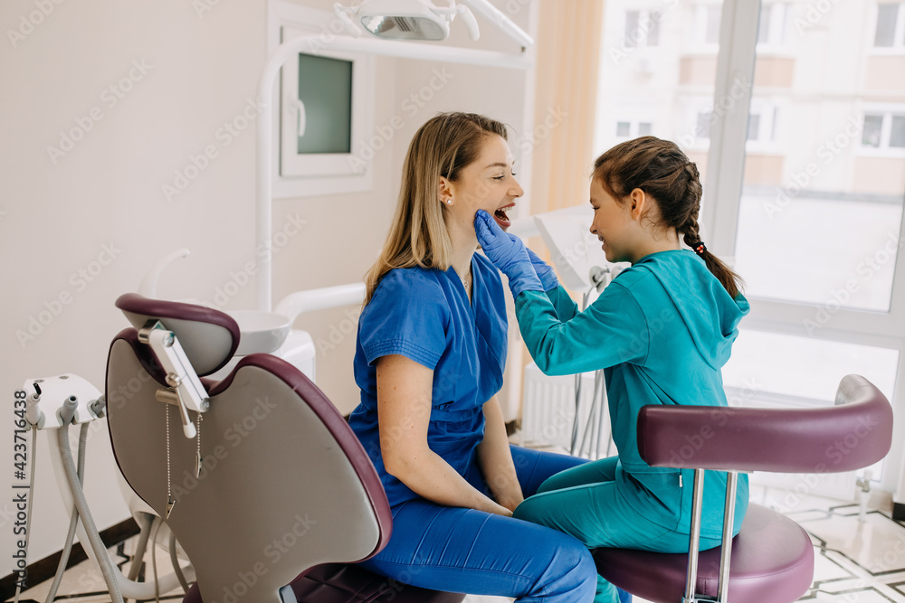 Little girl stomatologist with a patient at a dental clinic checking teeth. Little girl stomatologist with a patient at a dental clinic checking teeth.
