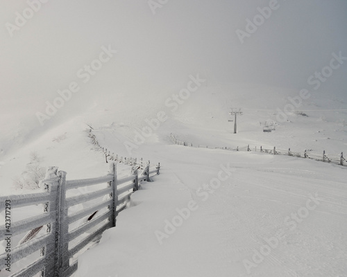 landscape with a fence in a misty mountain covered with snow