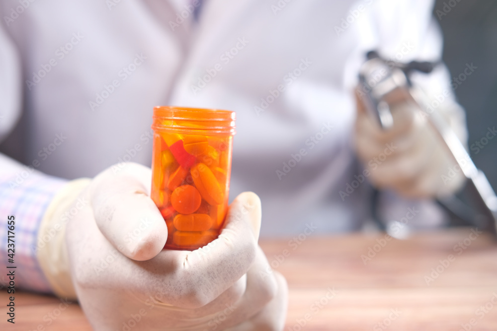 doctor hand in protective gloves holding pill container doctor hand in protective gloves holding pill container